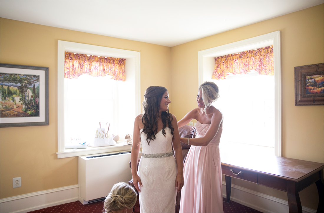 bride getting into dress with maid of honor, Normandy Farms Wedding 