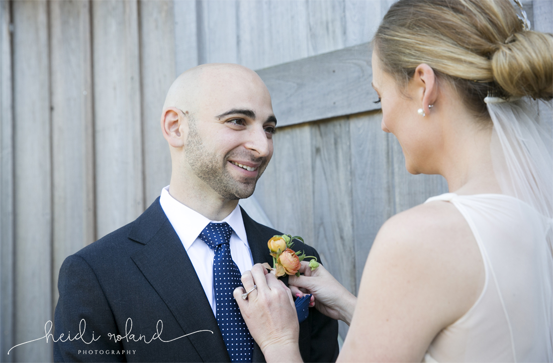 Willow Creek Winery Wedding bride putting on groom's boutonniere 