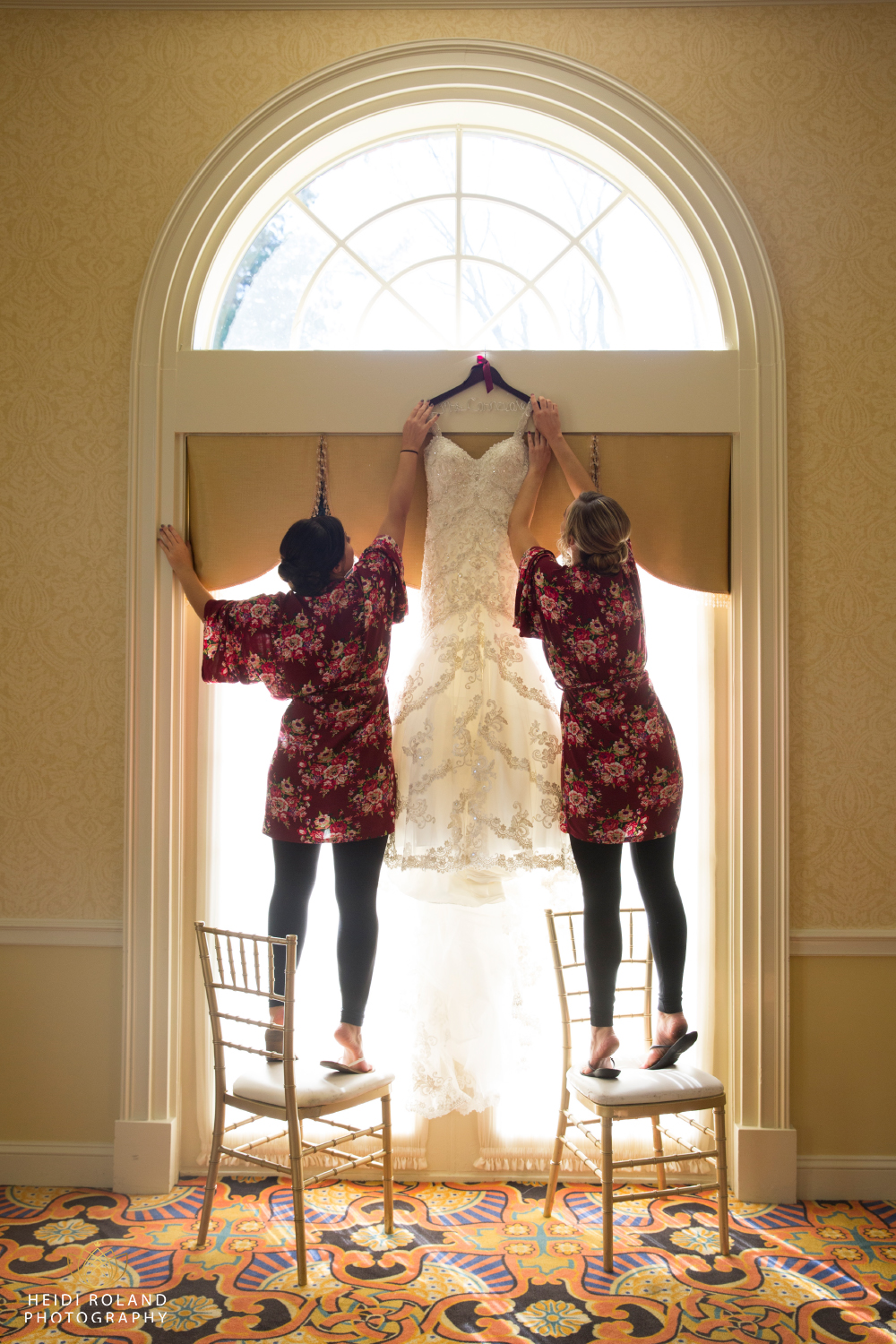 bridesmaids in robes hang wedding dress at Spring Mill Manor Wedding