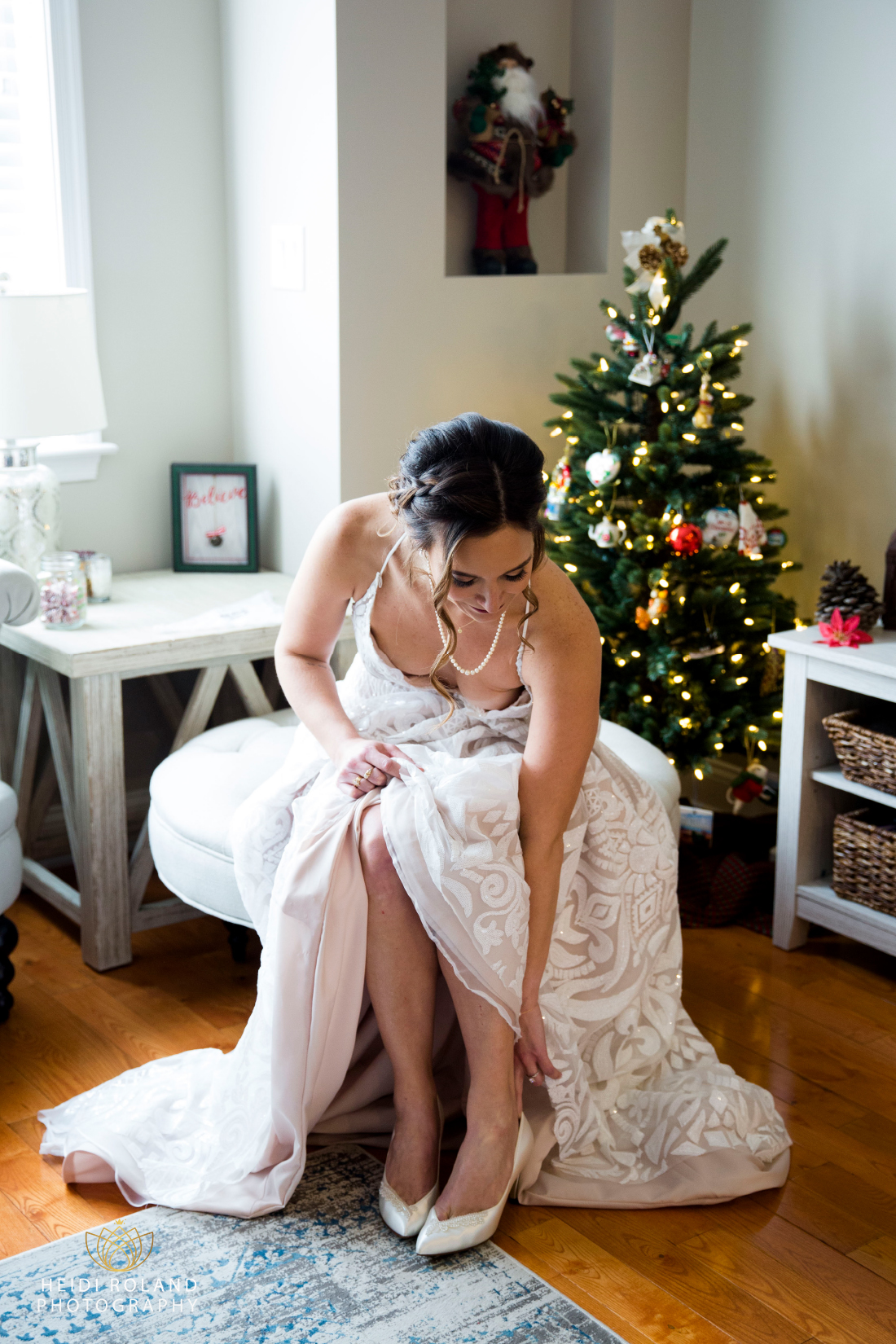 Bride putting on shoes in front of Christmas tree