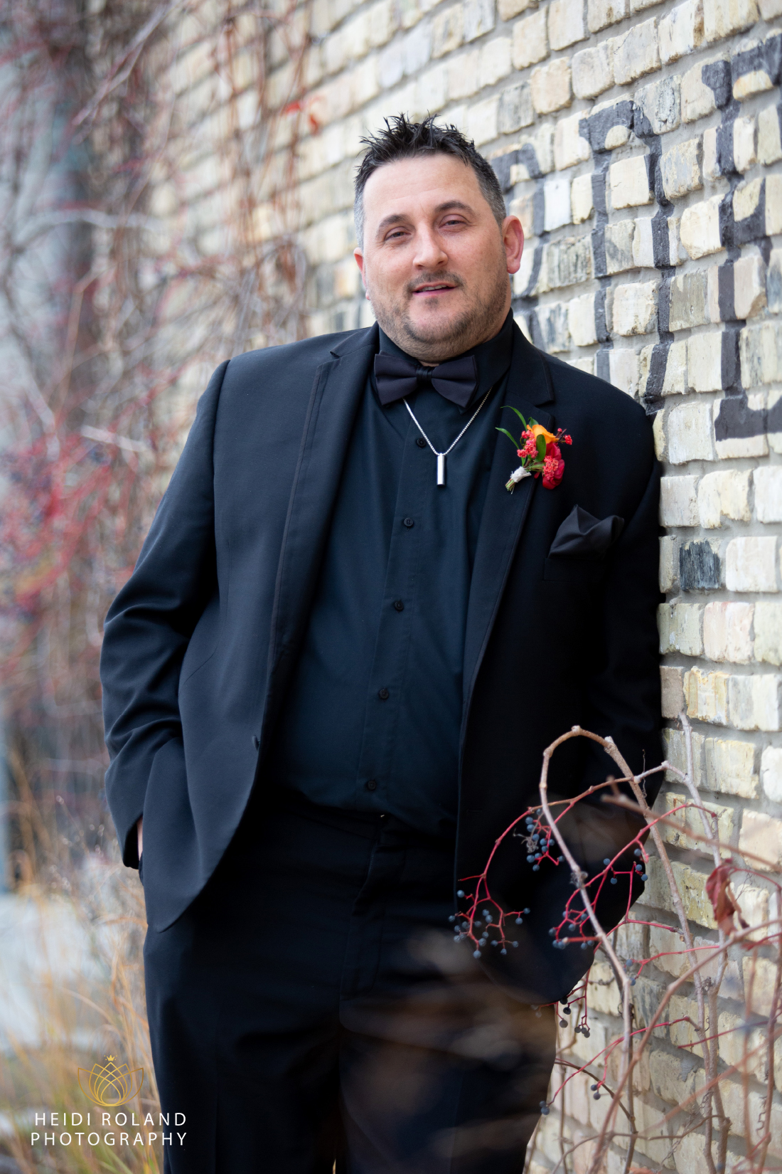 Groom in all black suit with colorful boutonniere