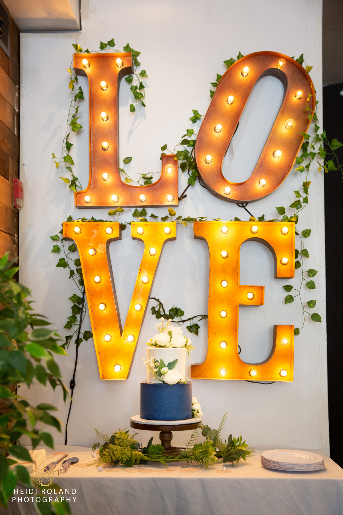 wedding cake in front of light up love sign in philadelphia