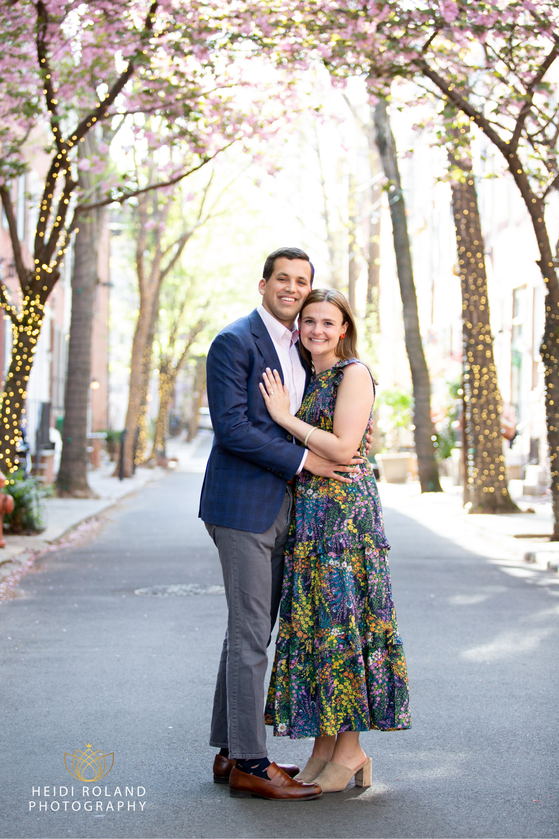 Newly engaged couple on Addison Street in philadelphia surrounded by cherry blossoms by Heidi Roland Photography