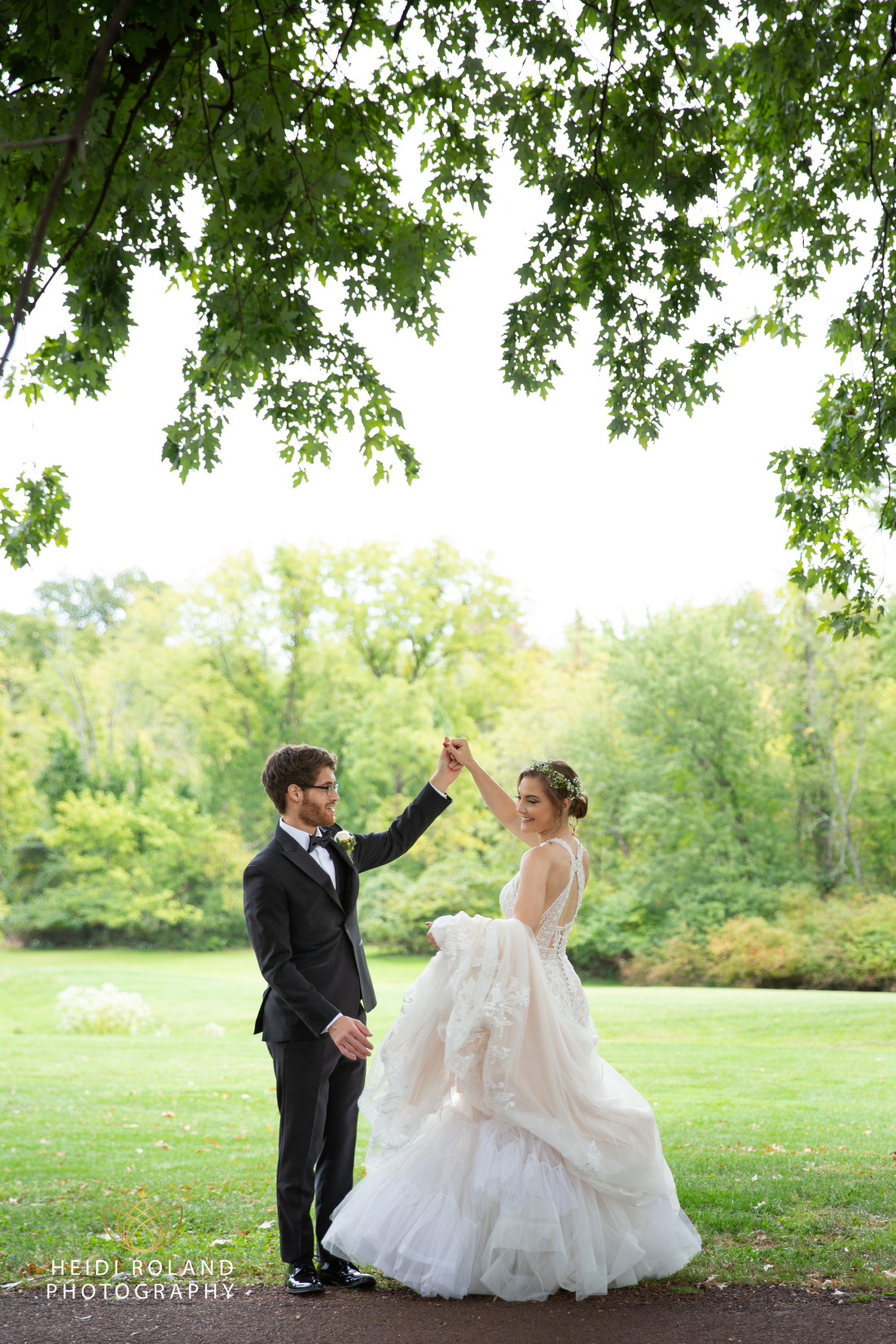 Groom spinning bride on grass path in philadelphia suburbs wedding