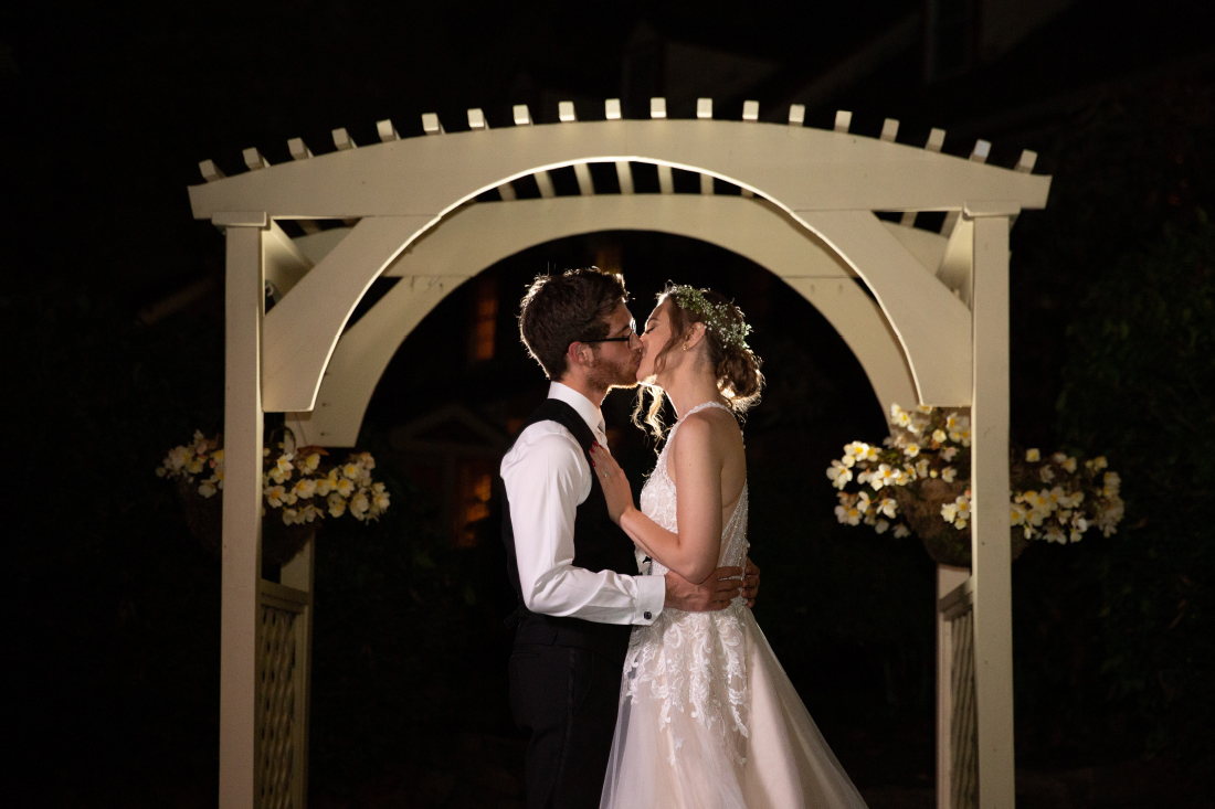 Bride and groom sharing a kiss outdoors at night by Heidi Roland Photography