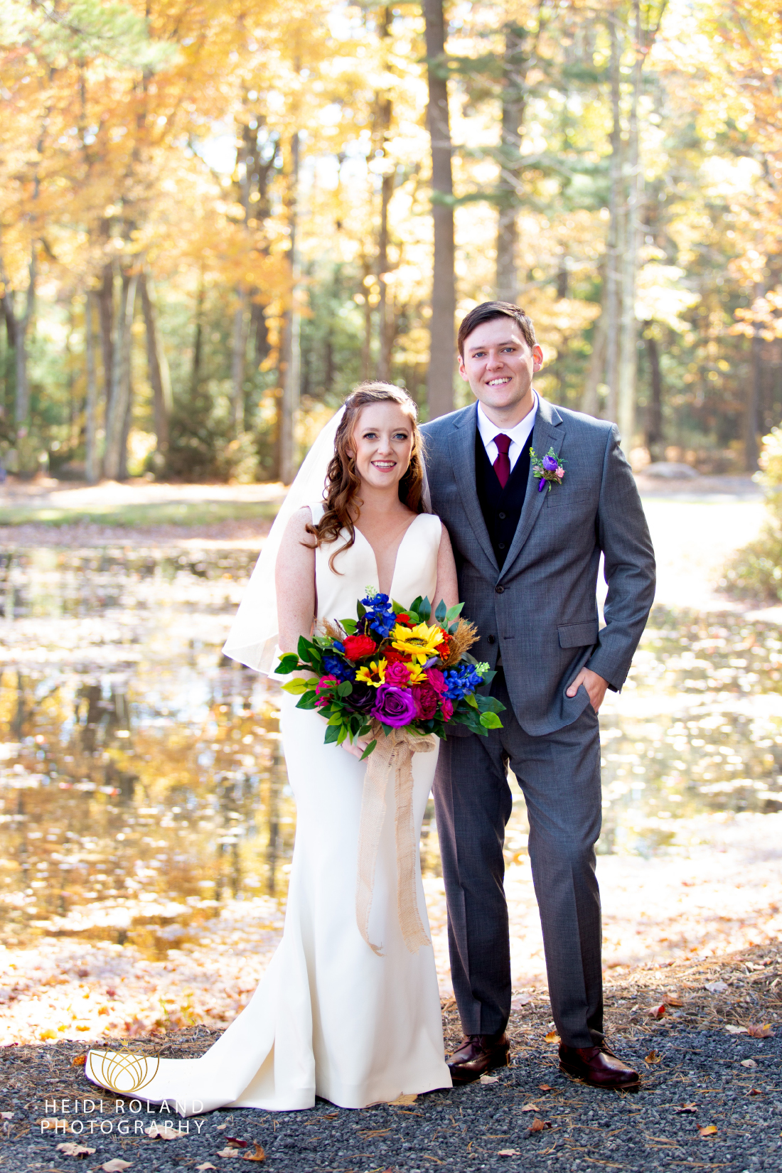 Bride holding bright floral bouquet standing with groom in the woods before fall wedding in Mount Pocono PA