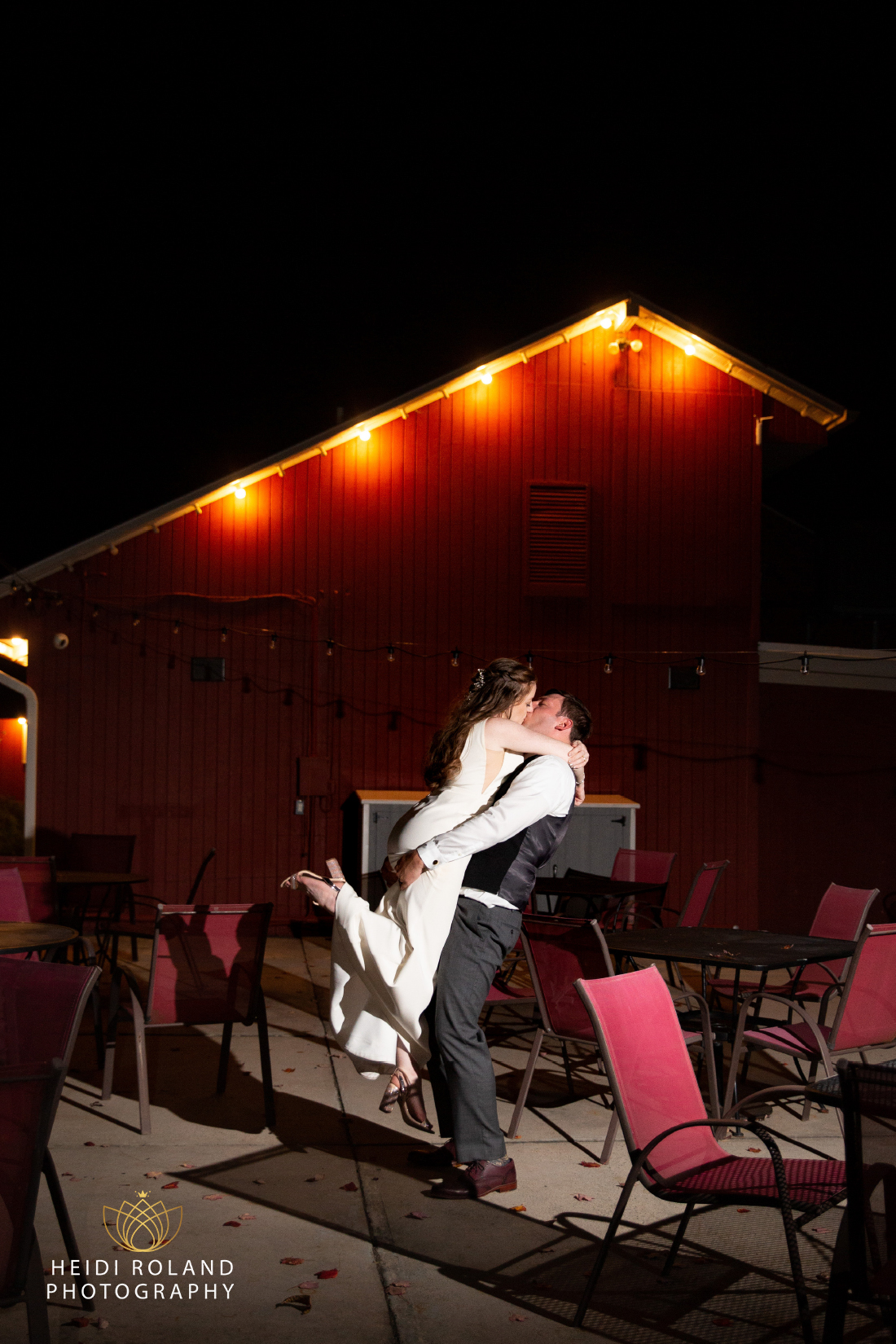 Groom lifting bride and kissing at night outside of wedding reception at Memorytown 