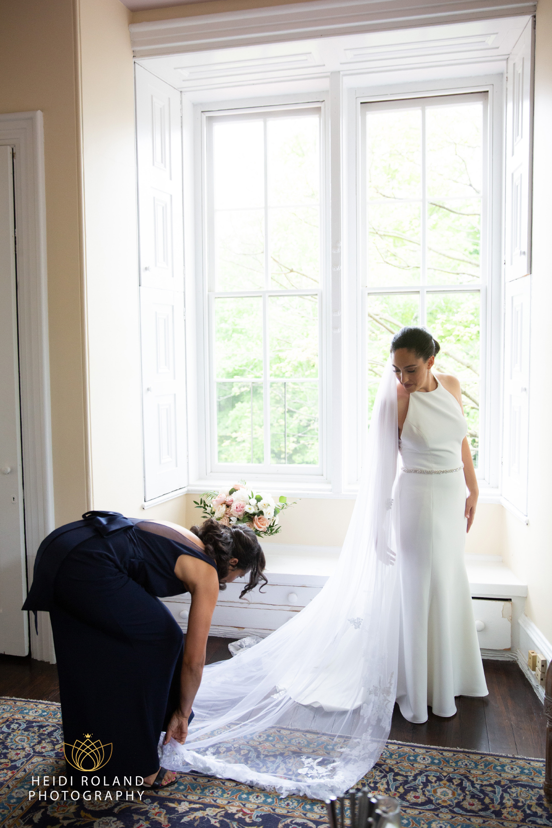 Woman helping bride with wedding dress train indoors at Portico Awbury Arboretum by Heidi Roland Photography