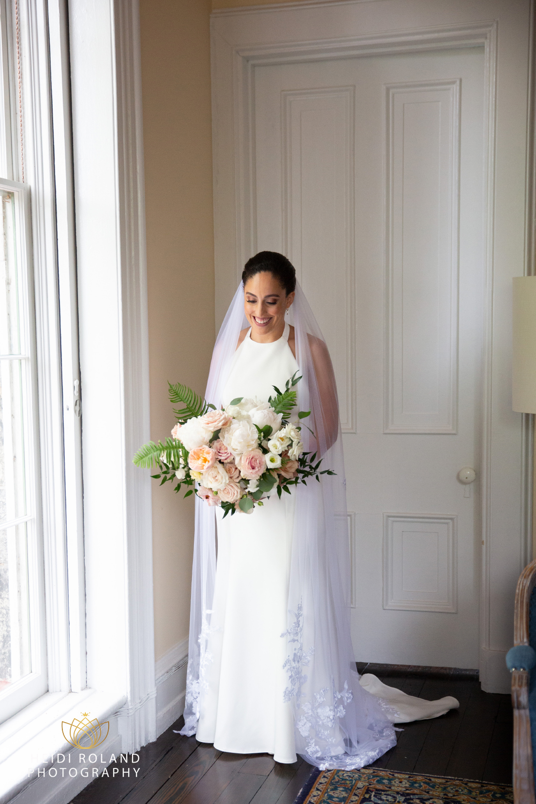 Bride in her wedding dress holding flower bouquet inside of portico in Philly
