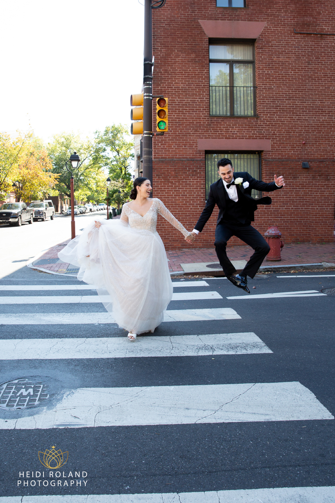 Groom clicking his heels together with excitement while crossing the street with the bride in Philadelphia