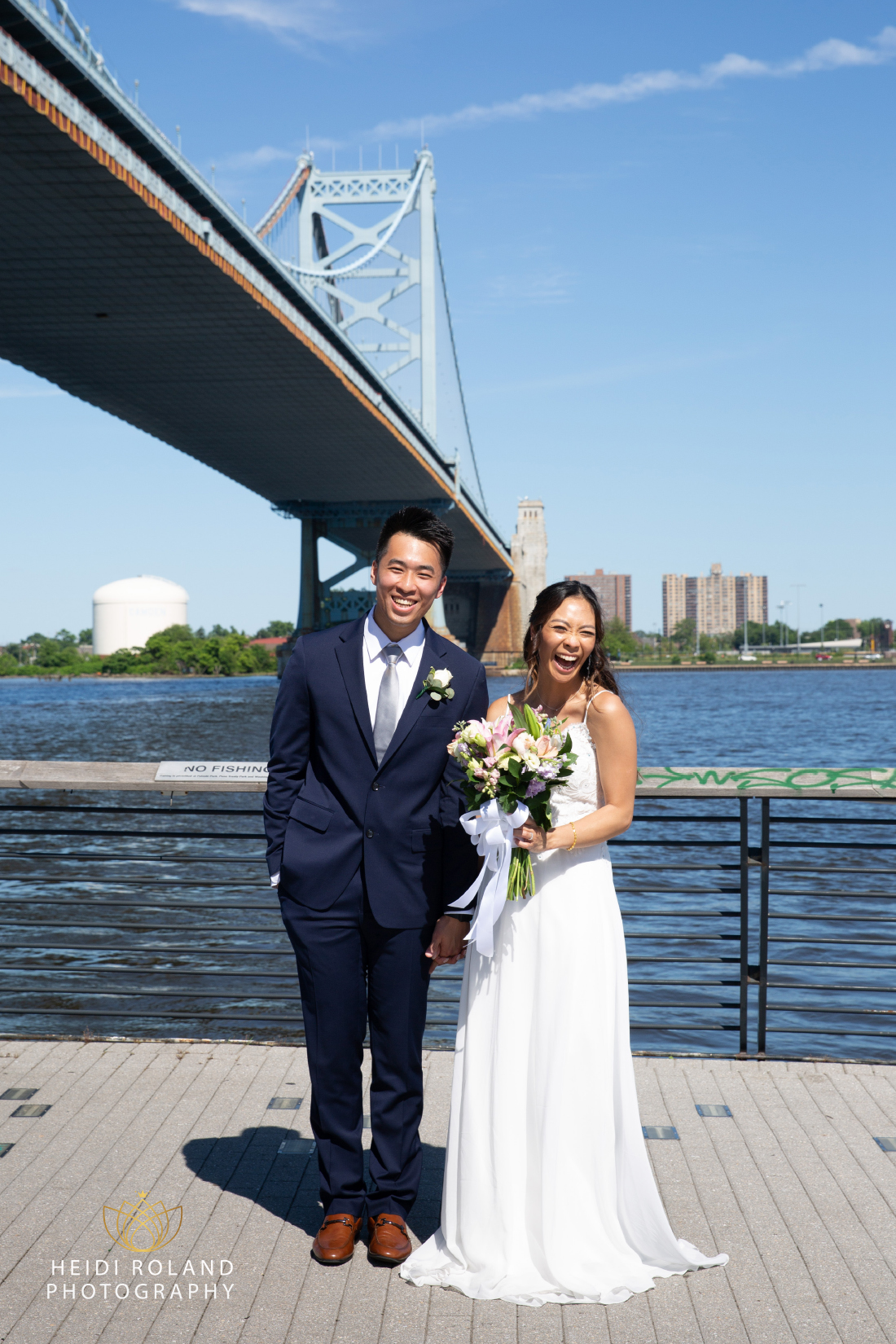 Smiling couple on their wedding day at Race Street Pier with Ben Franklin bridge in the background
