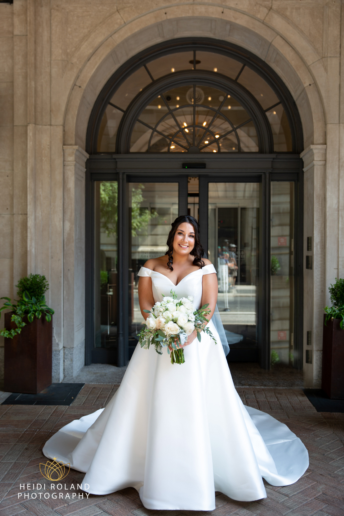 Bride outside philadelphia hotel in wedding dress with flowers