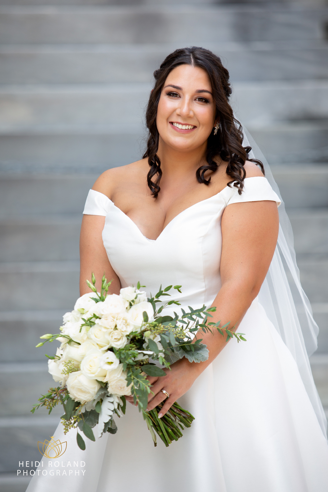 Bride smiling while holding flowers outside the merchant exchange in Philly by Heidi Roland Photography 