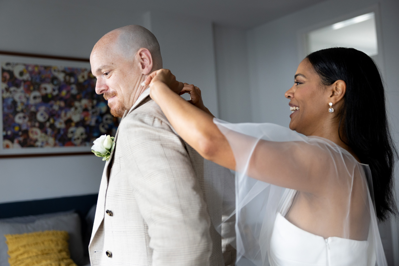 bride helping groom get dressed fro wedding 